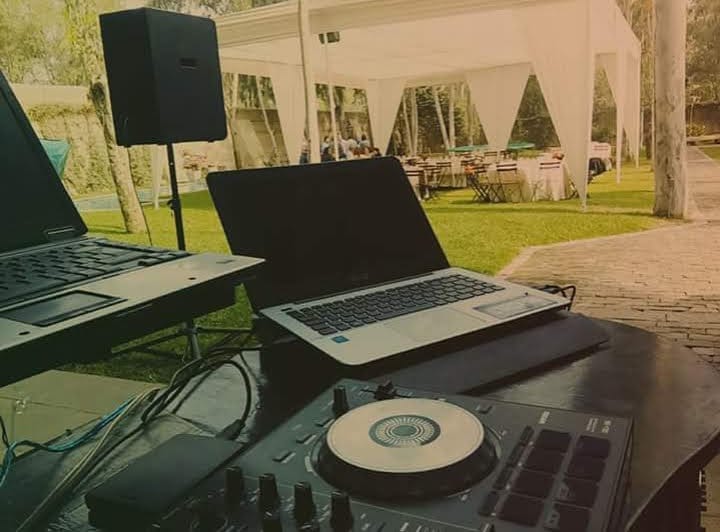 Setup de DJ con dos laptops y controlador en evento al aire libre en Cieneguilla