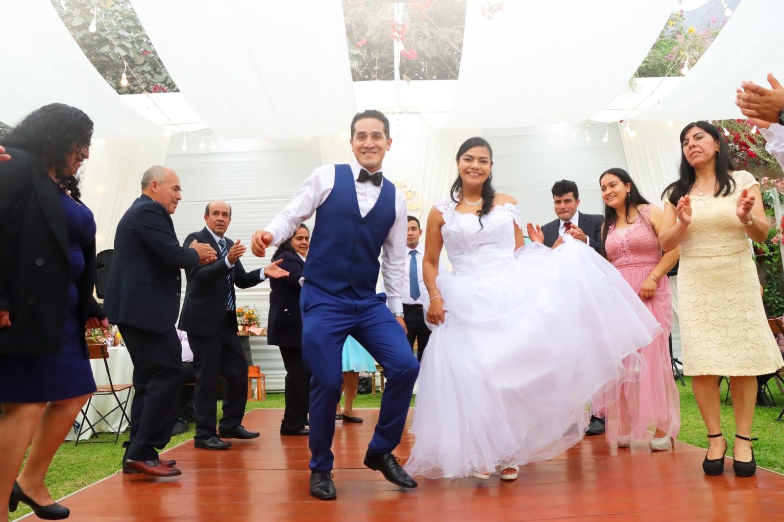 Pareja de novios bailando durante su boda en Cieneguilla, con la novia en un vestido blanco y el novio en un traje azul.