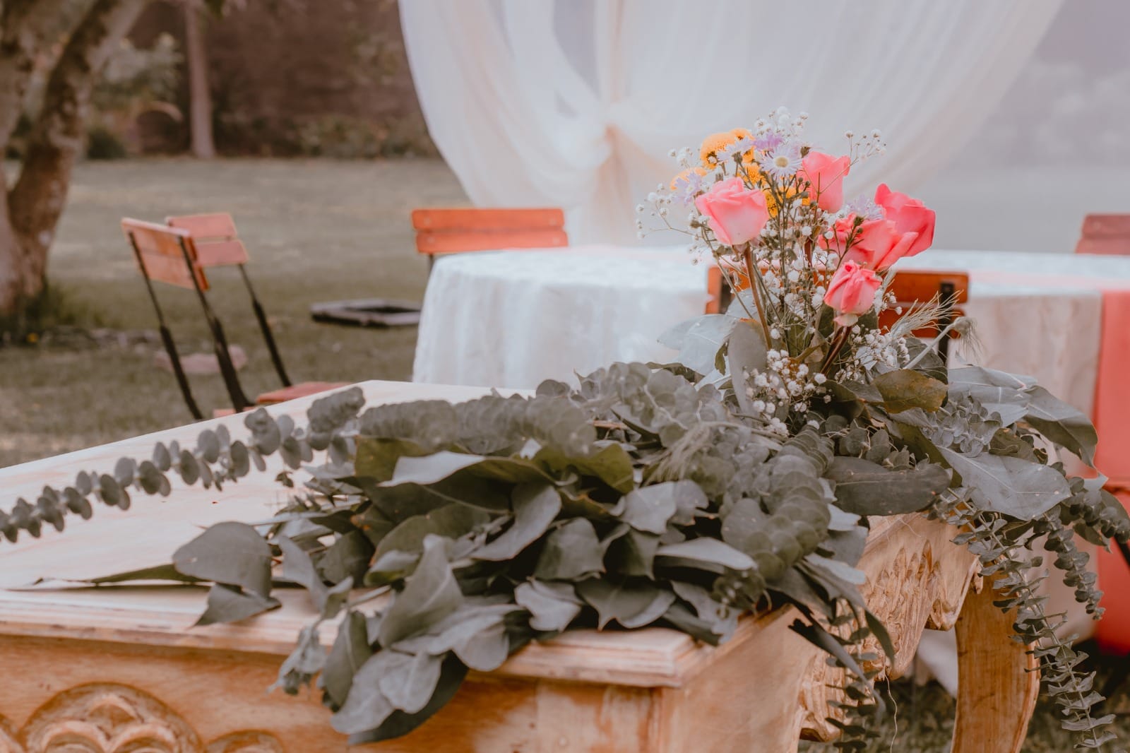 Arreglo floral con rosas rosas, flores amarillas y aliento de bebé en una mesa de madera en una boda en Cieneguilla