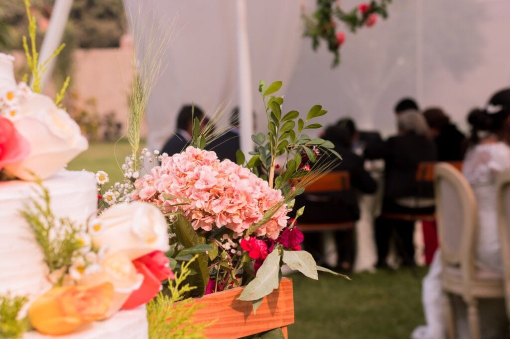 boda_floral_evento_cieneguilla Arreglo floral y pastel de boda con fondo de personas en un evento en Cieneguilla