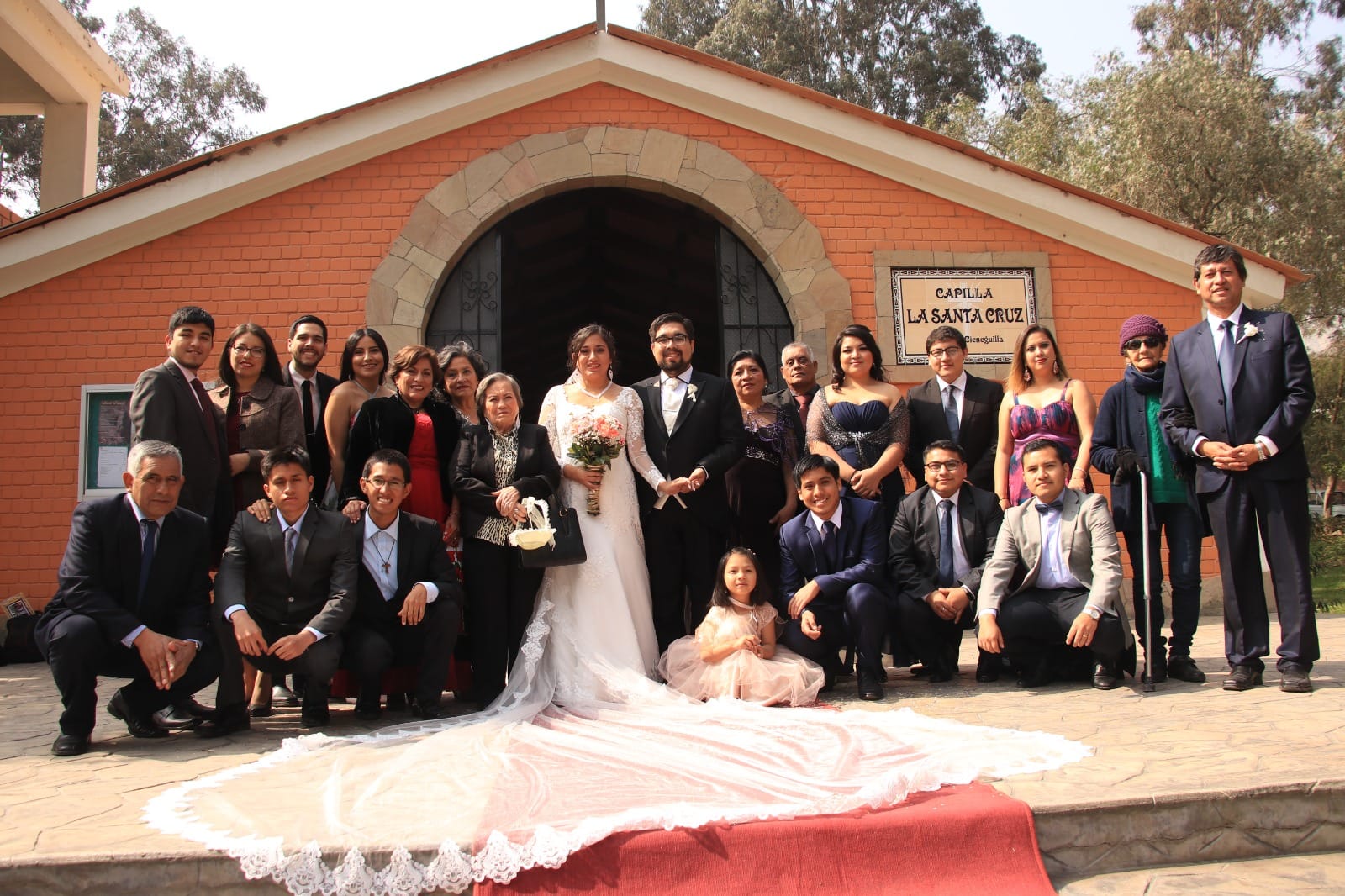 Grupo de personas posando frente a la Capilla La Santa Cruz en Cieneguilla durante una boda