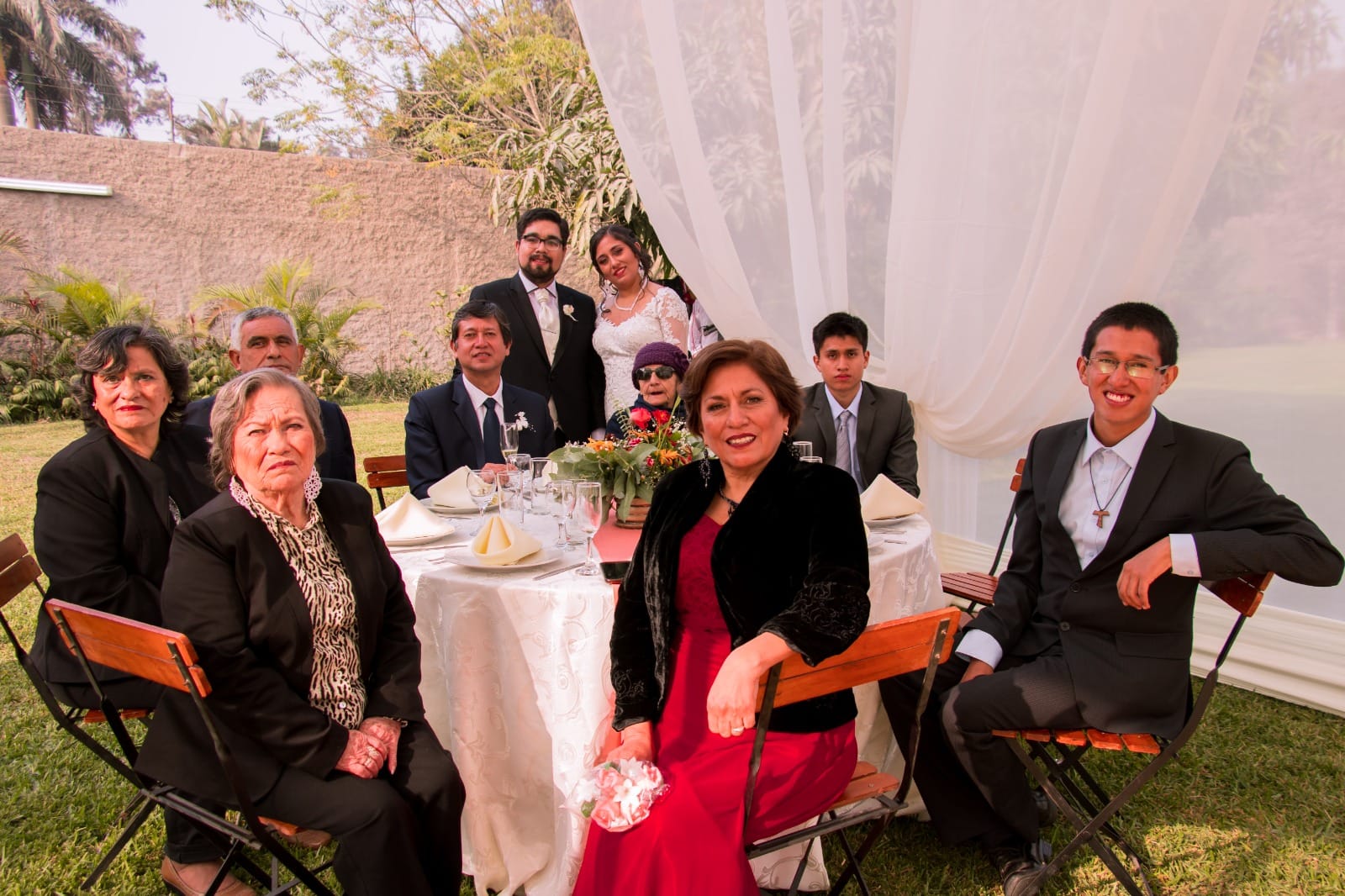 Grupo de personas vestidas de manera formal alrededor de una mesa en un evento al aire libre en Cieneguilla