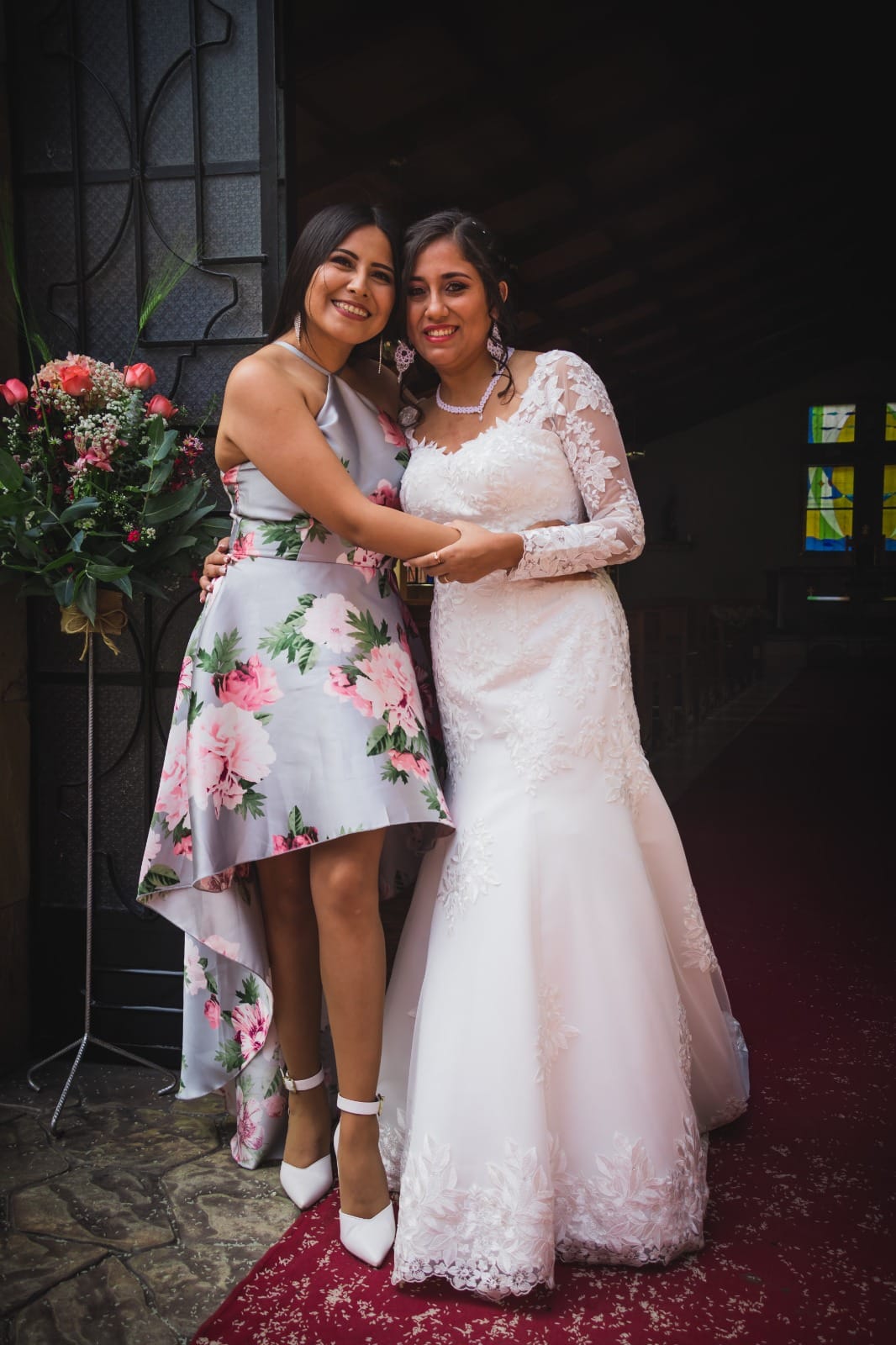 Persona ajustando el vestido de una novia con detalles de encaje floral