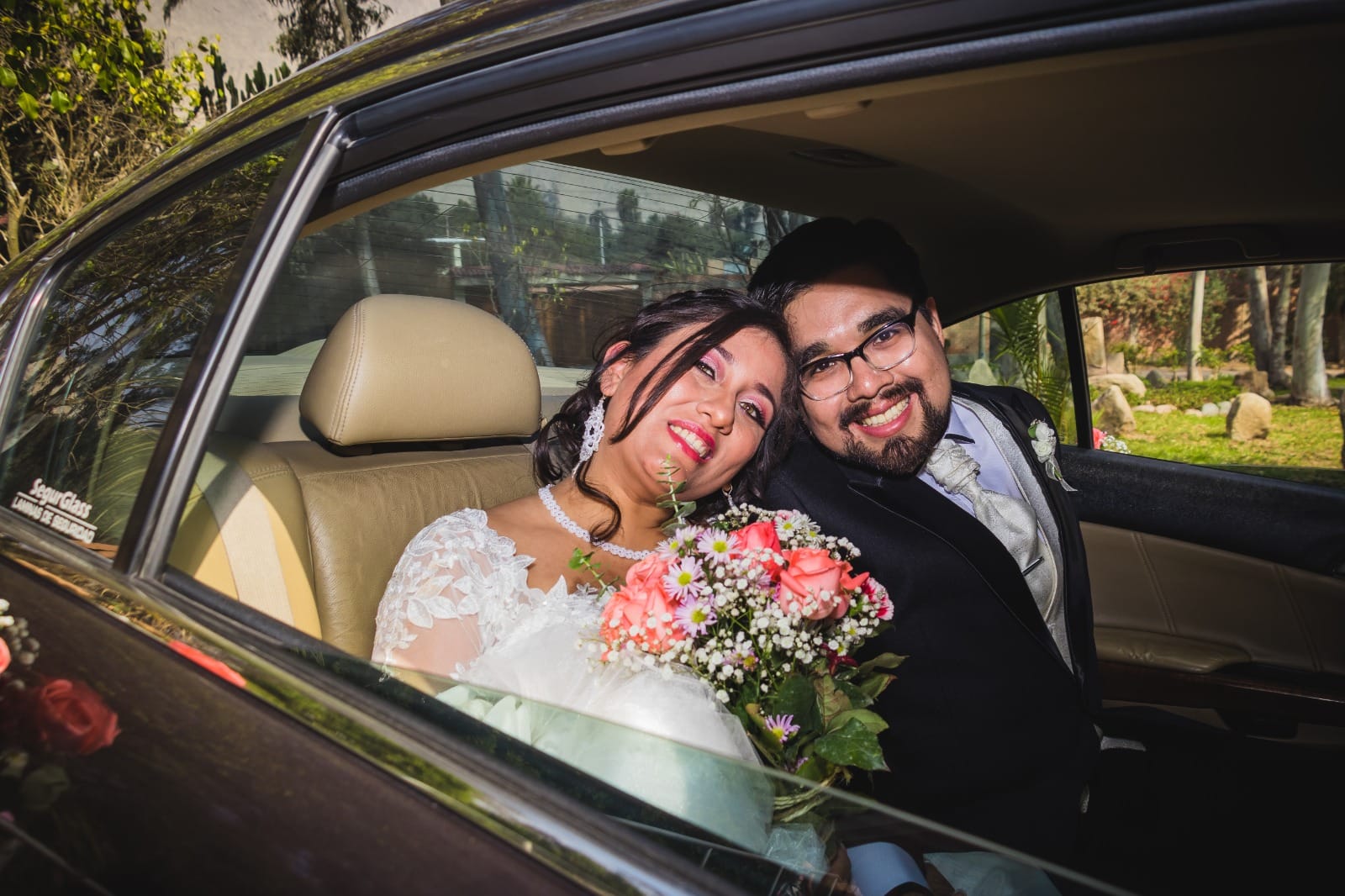 Pareja de novios sentados en el asiento trasero de un automóvil