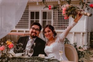 Pareja de novios sentados en una mesa decorada con flores durante su boda en Cieneguilla