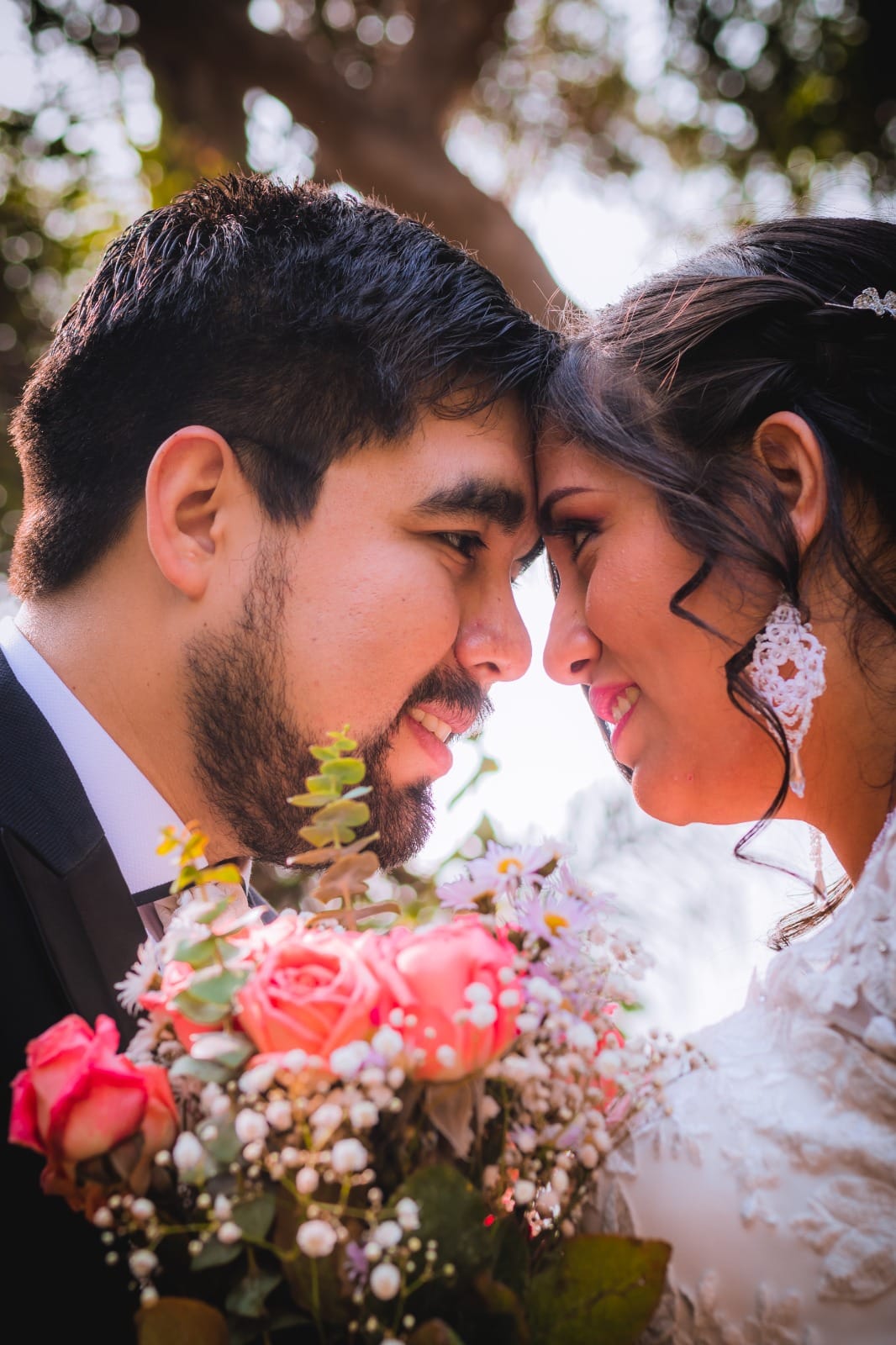 Pareja en traje oscuro y vestido blanco sosteniendo un ramo de flores en una boda en Cieneguilla
