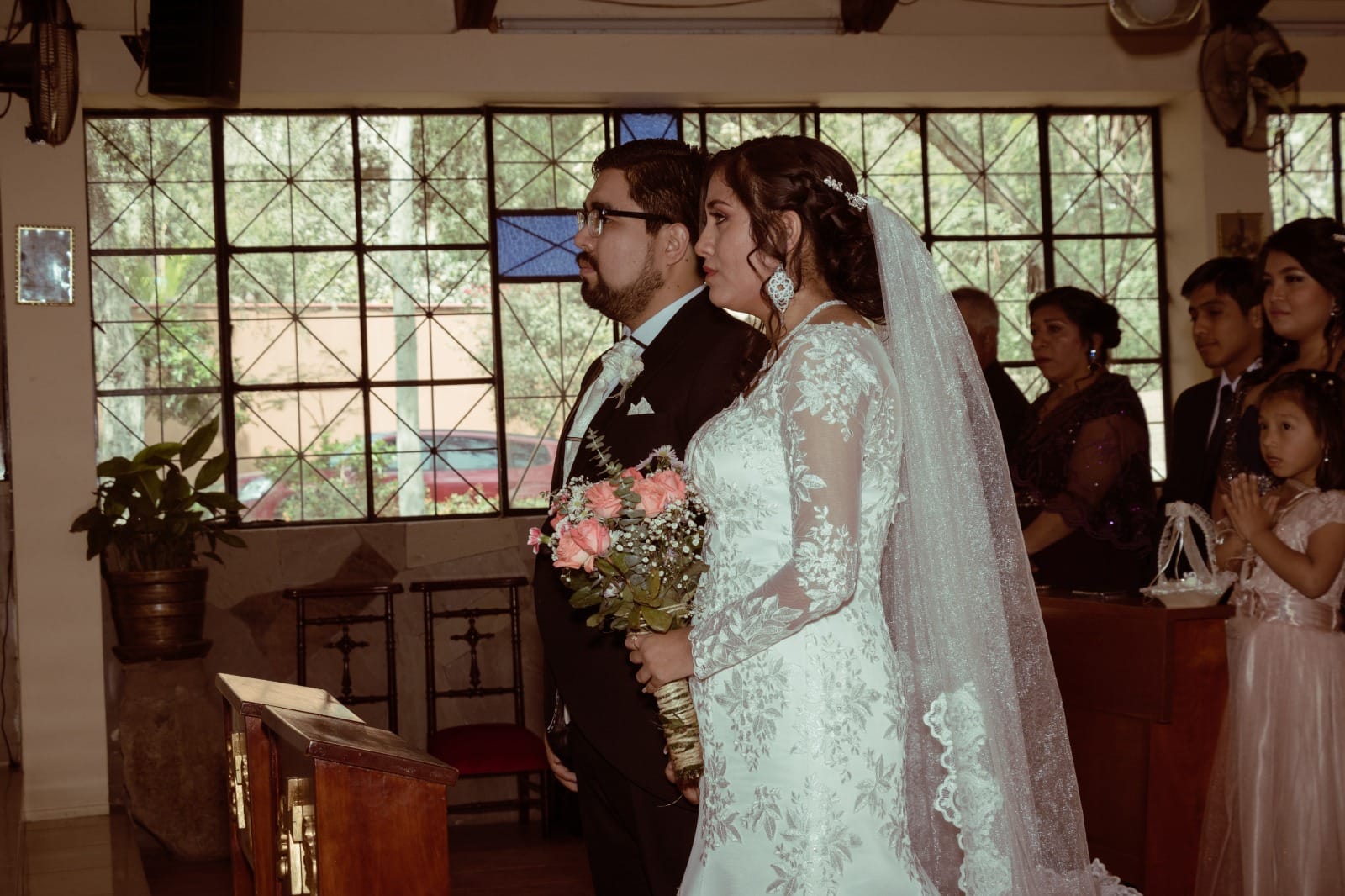 Pareja de novios en traje oscuro y vestido blanco en una ceremonia de boda en una iglesia en Cieneguilla