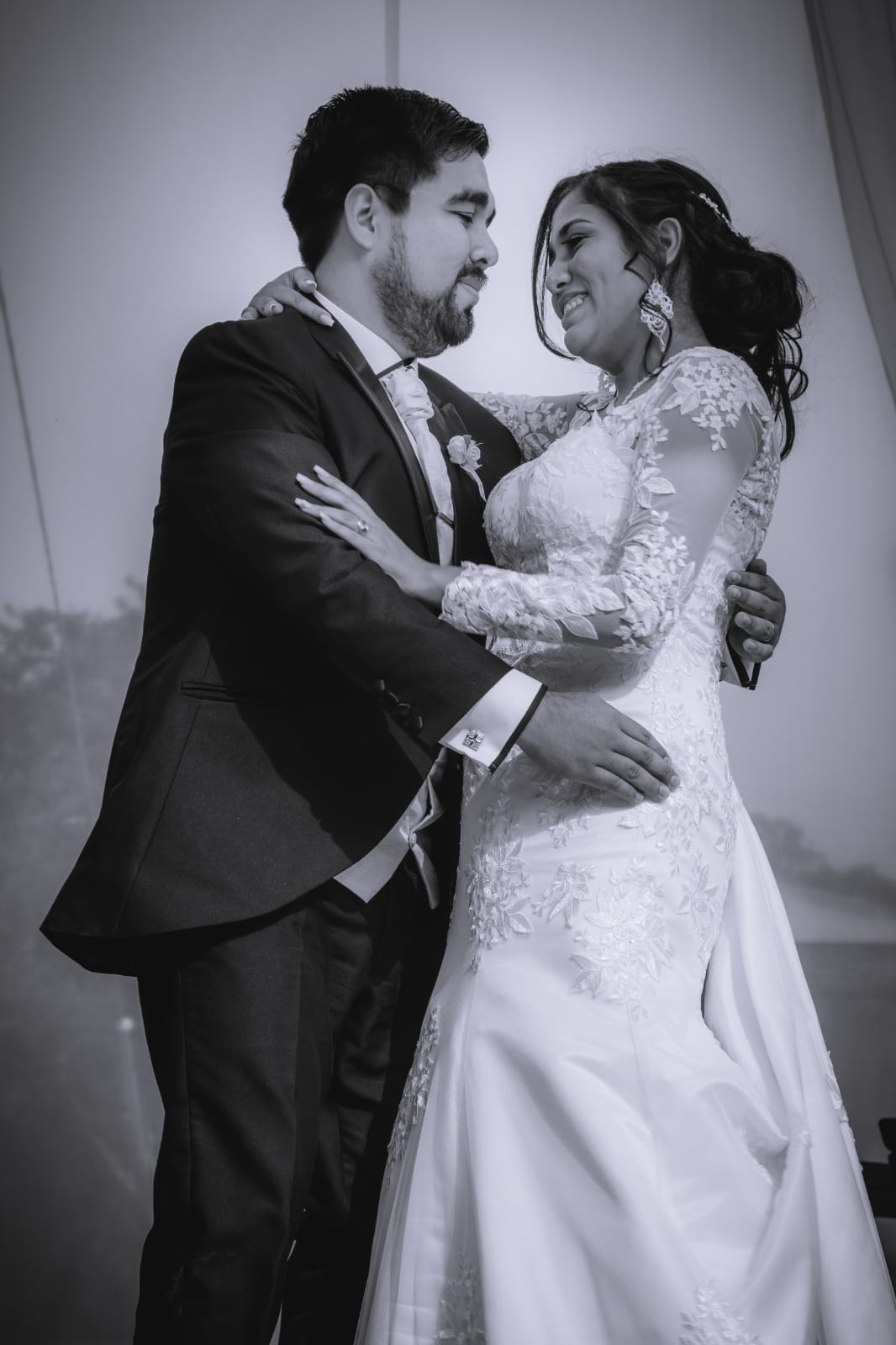 Pareja de novios en traje oscuro y vestido blanco con encaje en una boda al aire libre en Cieneguilla