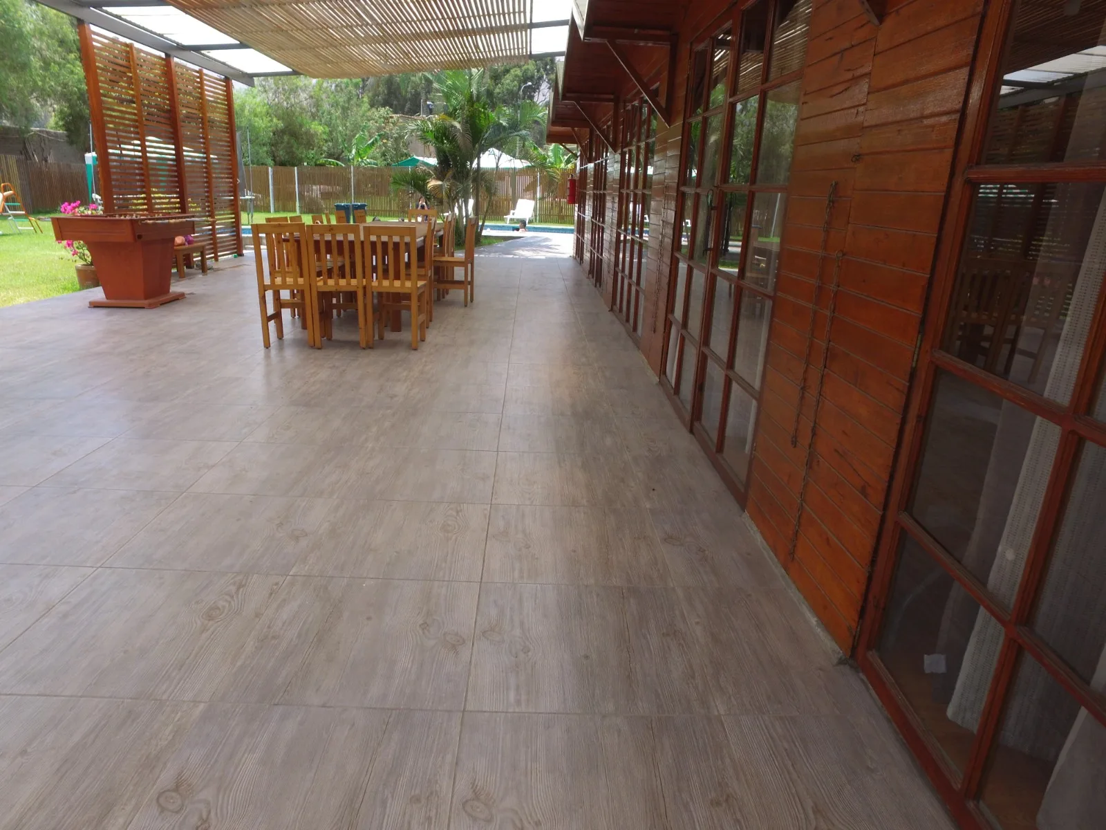 Comedor exterior rústico en una casa en alquiler en Cieneguilla con mesas y sillas de madera, sofás marrones y decoración vegetal.