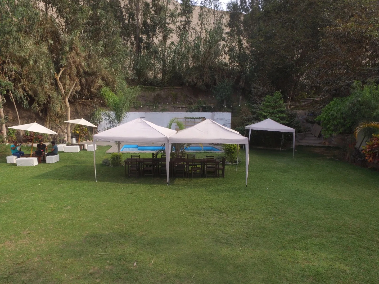 Configuración exterior con césped, carpas blancas, sillas y mesas para un evento en una casa en alquiler en Cieneguilla.