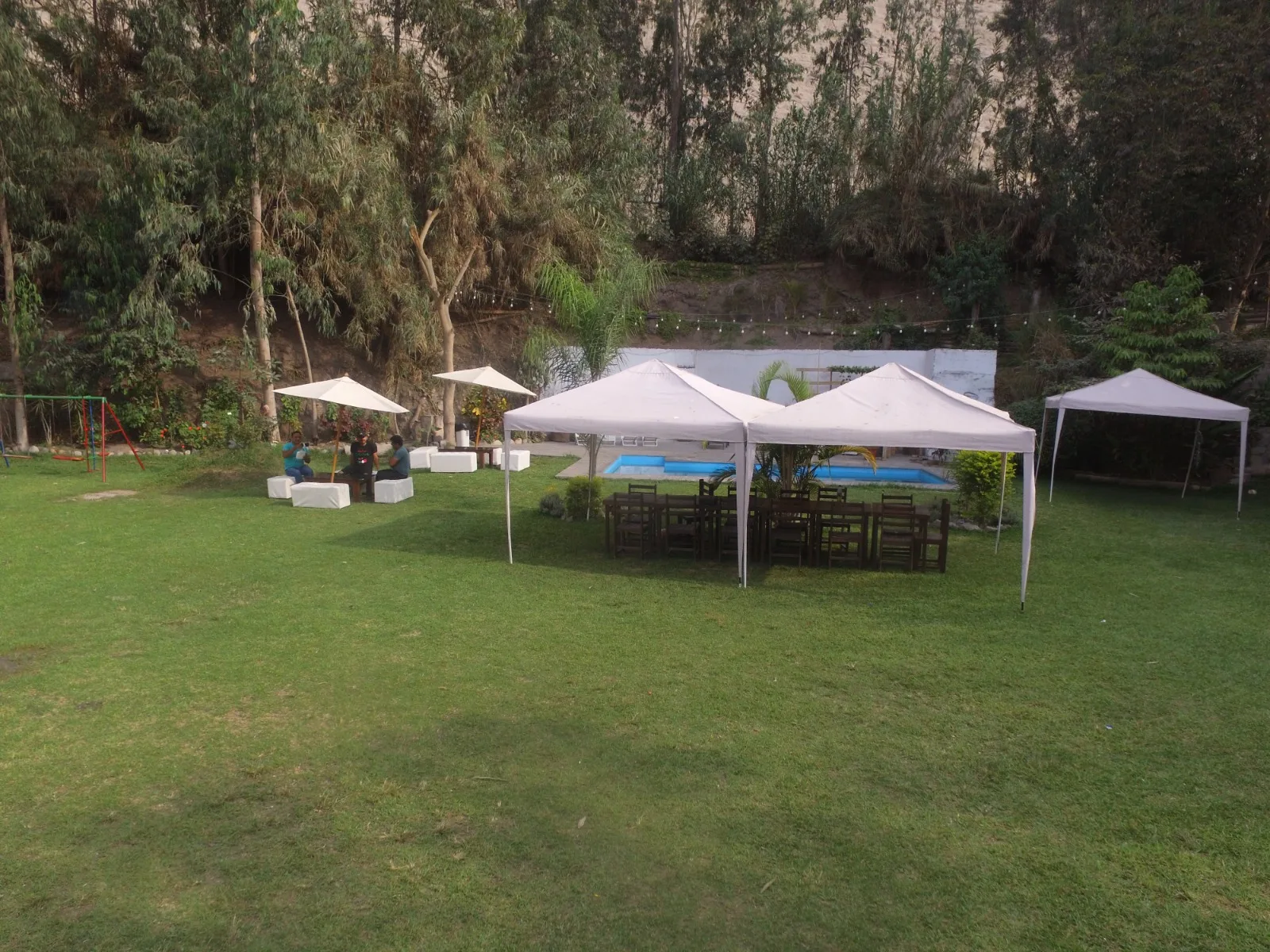 Configuración exterior para evento con césped, carpas blancas, sillas y mesas en una casa en alquiler en Cieneguilla.