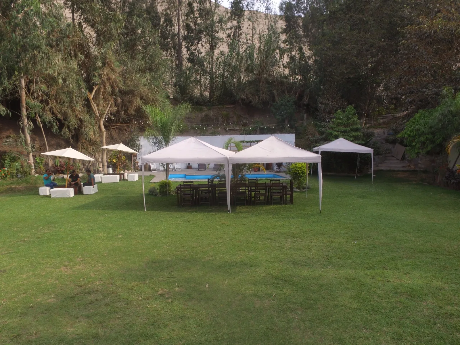 Configuración exterior para evento con césped, carpas blancas, sillas y mesas en una casa en alquiler en Cieneguilla.