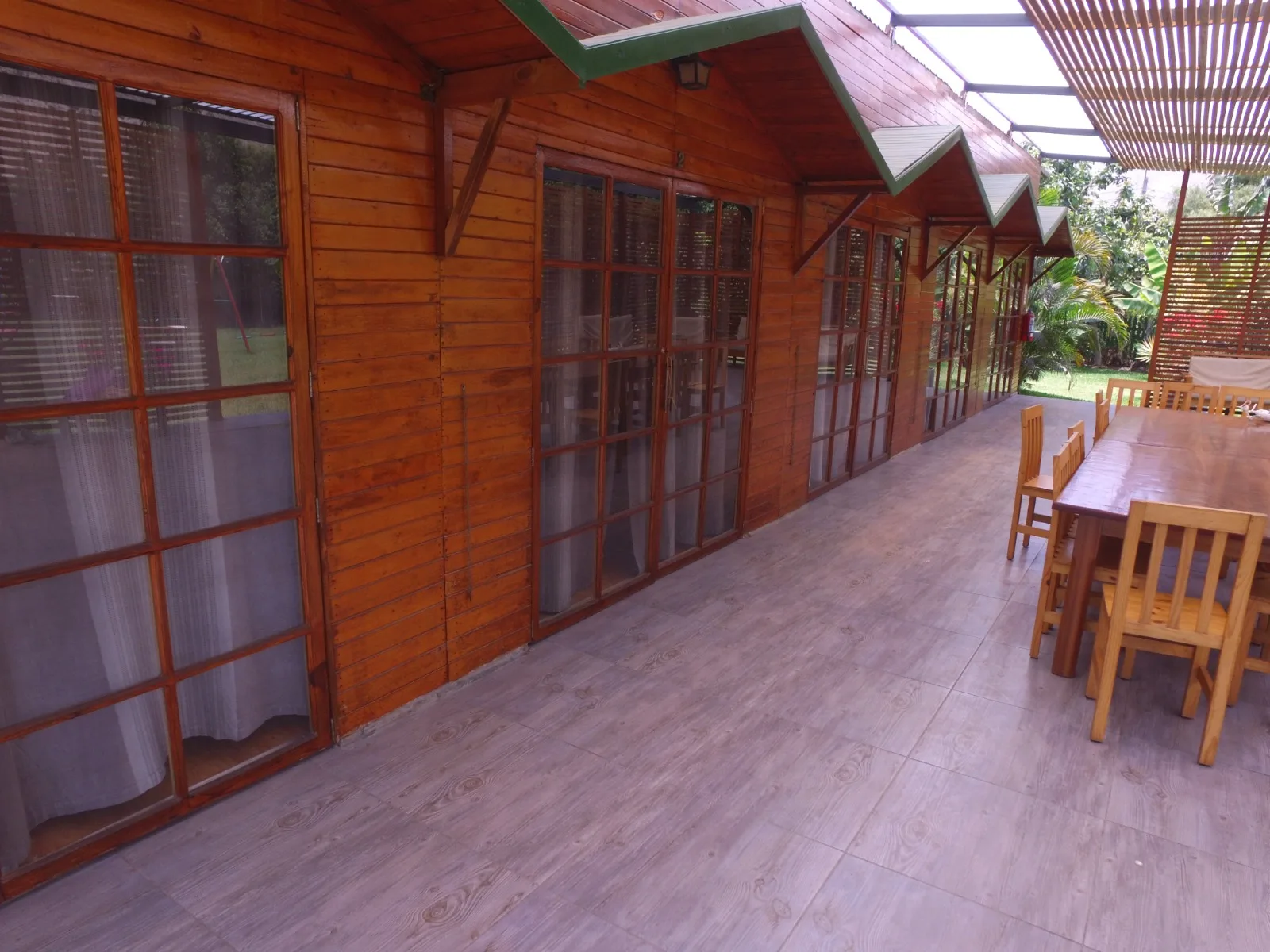 Comedor exterior con techo de madera y grandes ventanales en una casa en alquiler en Cieneguilla.