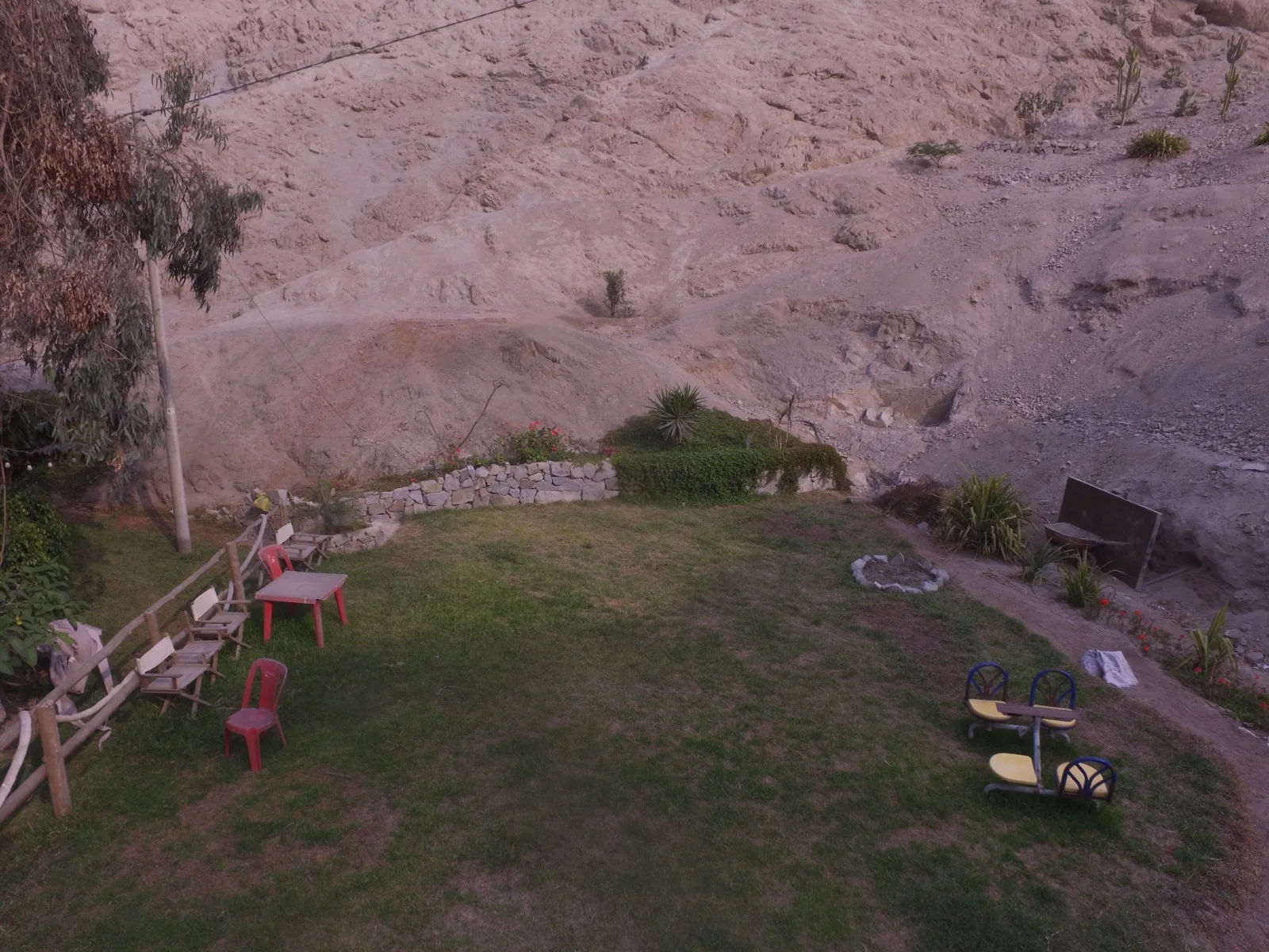 Comedor exterior rústico en una casa en alquiler en Cieneguilla con mesas y sillas de madera, sofás marrones y decoración vegetal.