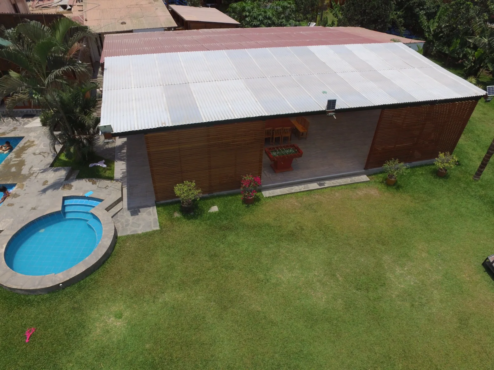 Vista aérea de una propiedad con edificio de madera, piscina circular y patio de piedra en Cieneguilla.