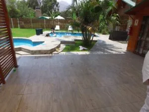 Área exterior con piscina y jacuzzi rodeados de vegetación, con personas disfrutando del agua en una casa en alquiler en Cieneguilla.