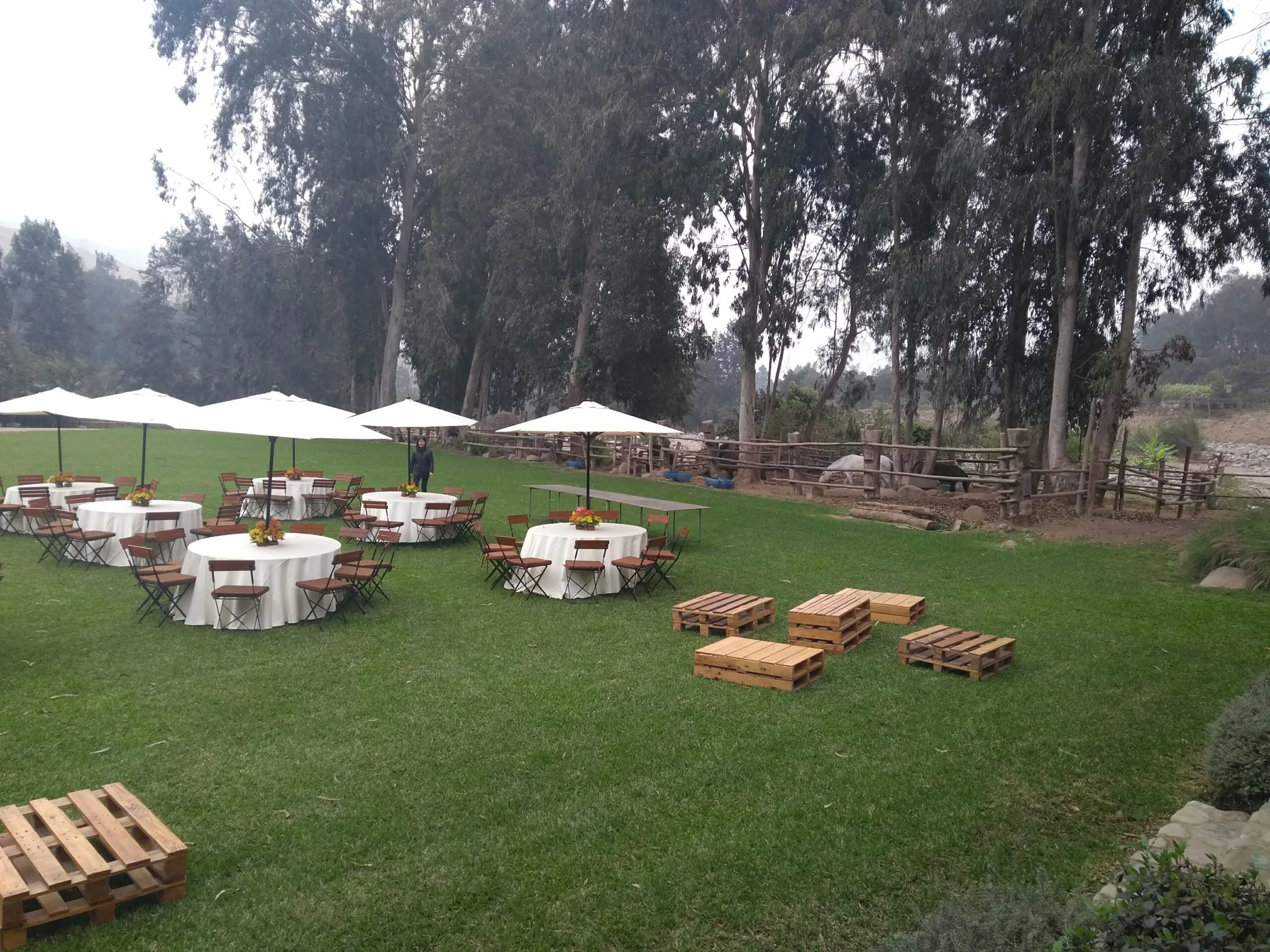Evento al aire libre con mesas redondas, sombrillas blancas y jardín en Cieneguilla