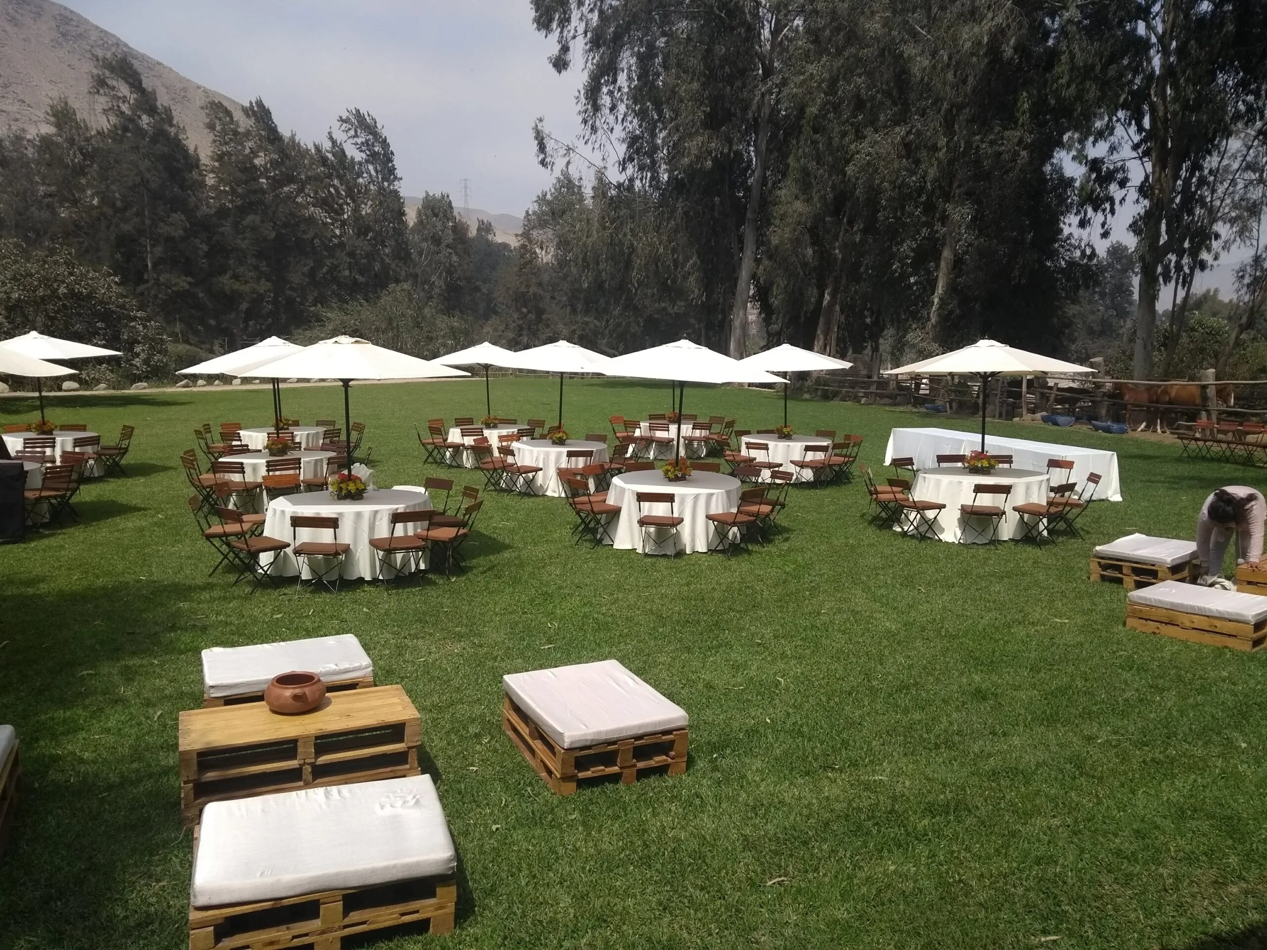 Evento al aire libre con mesas redondas, sombrillas blancas y jardín en Cieneguilla