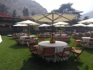 Evento al aire libre con mesas redondas, sombrillas blancas y jardín en Cieneguilla