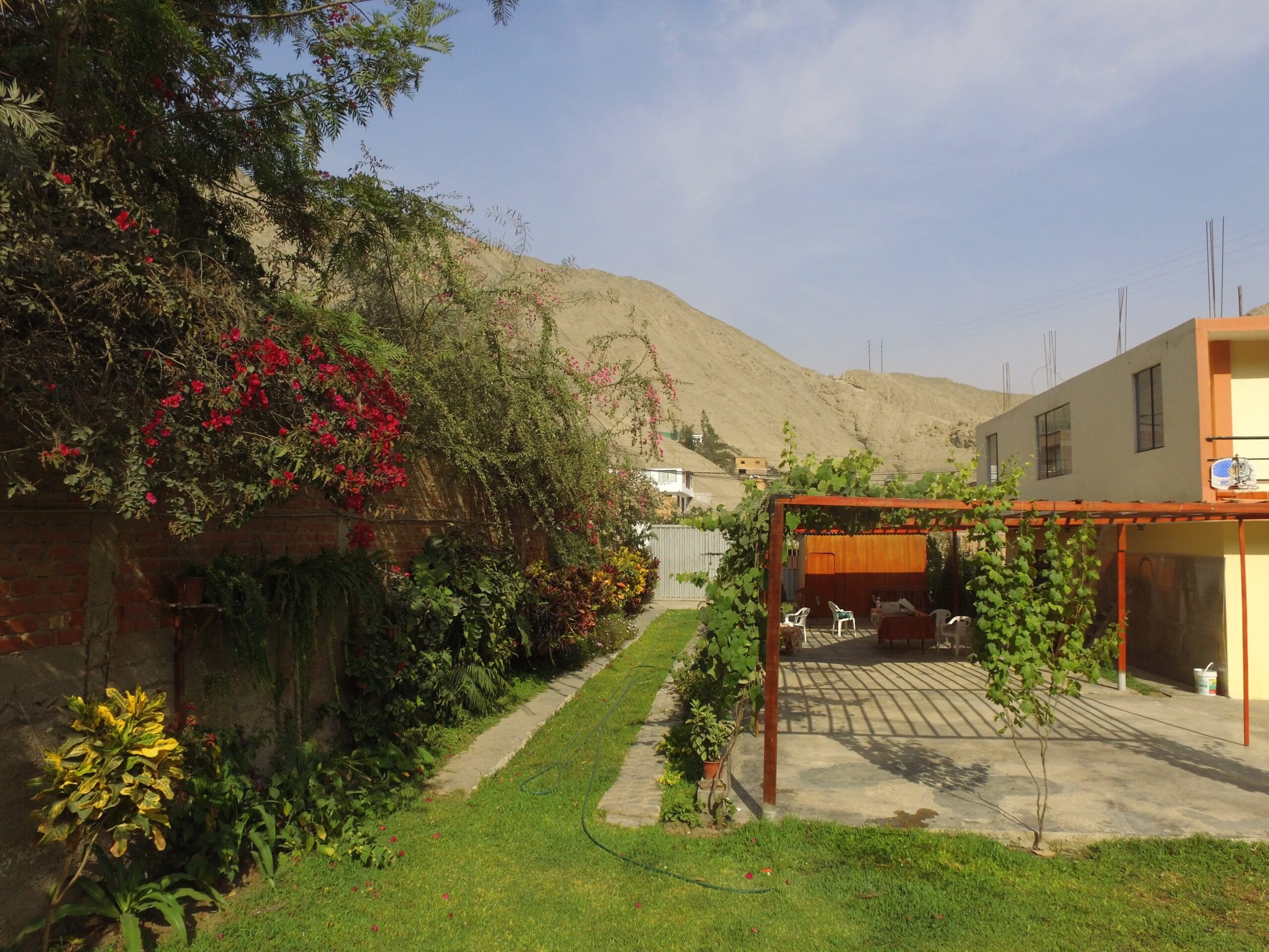 Jardín con pérgola, flores y muro de ladrillo para alquiler de eventos en Cieneguilla