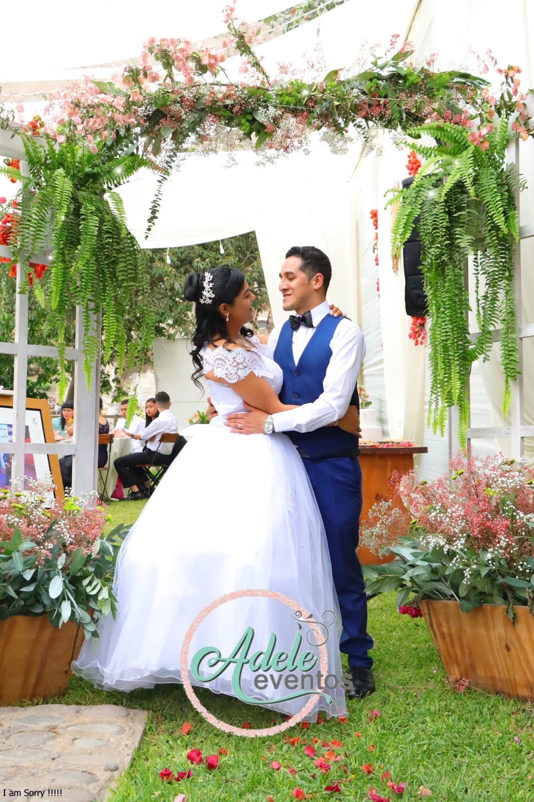 Pareja de novios posando en un jardín durante su boda en Cieneguilla, con la novia en un vestido blanco con encaje y el novio en un traje azul.