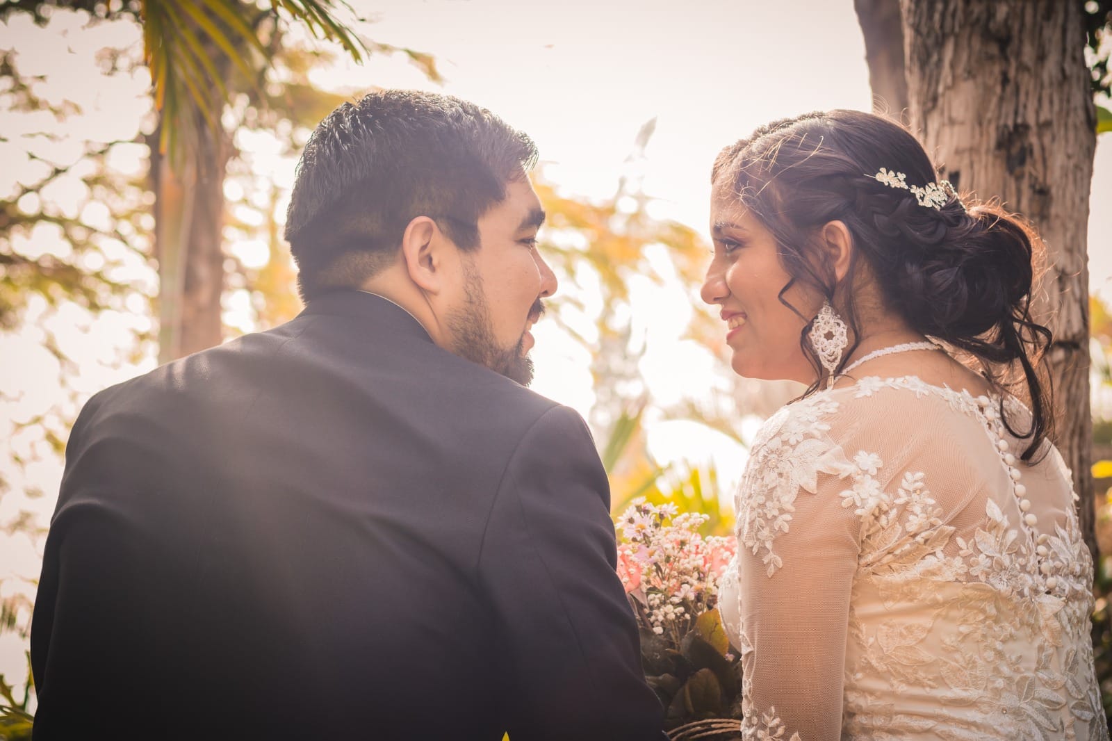 Pareja de espaldas en su boda en Cieneguilla, él con traje oscuro y ella con vestido de encaje blanco