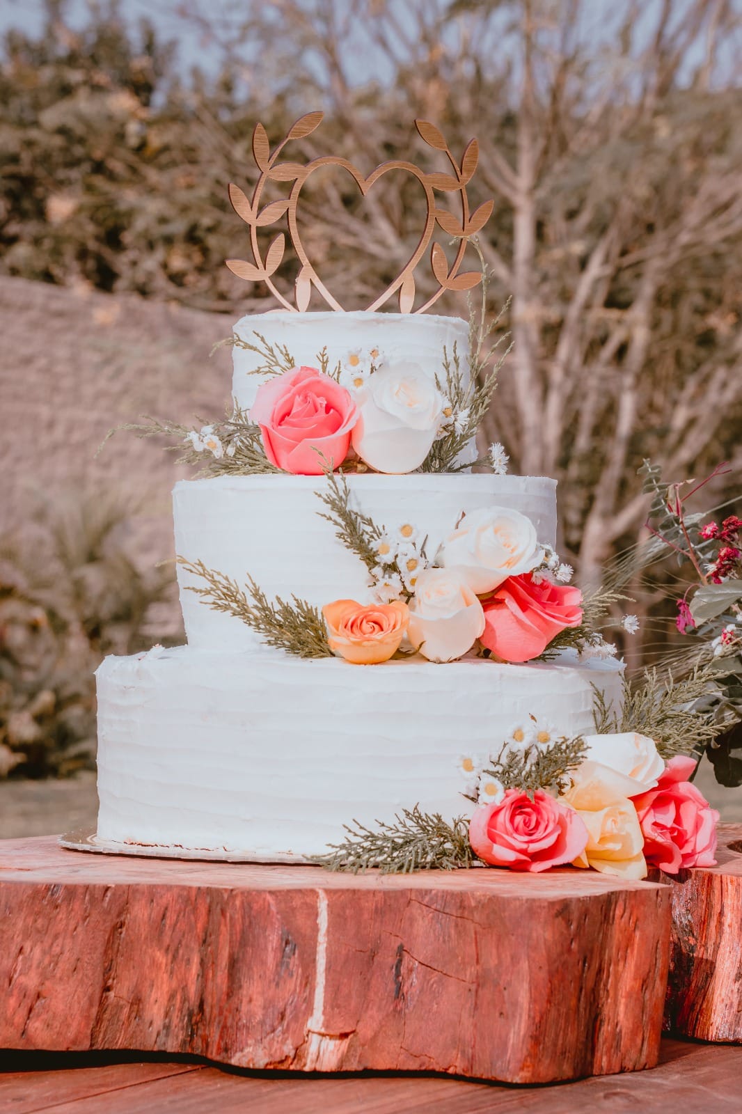Pastel de boda de tres niveles decorado con flores y vegetación