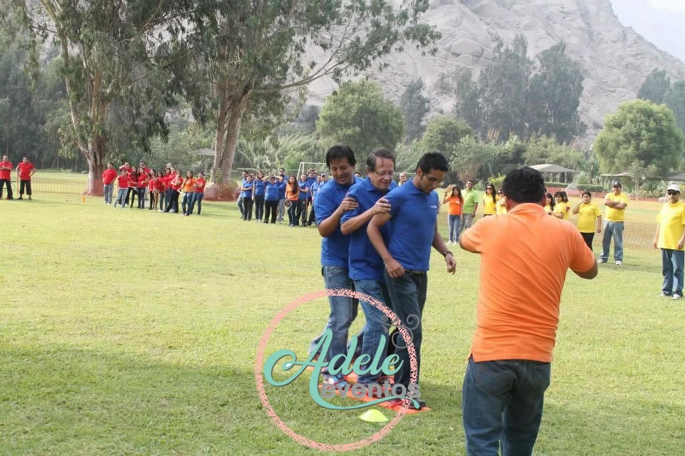 Equipo corporativo con camisetas azules participando en una competencia de integración al aire libre en Cieneguilla por Adele Eventos.
