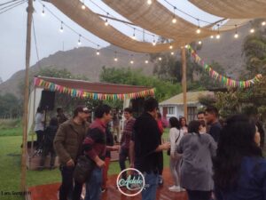 Colaboradores de una empresa compartiendo en una fiesta al aire libre iluminada con guirnaldas de luces durante un evento corporativo organizado por Adele Eventos en Cieneguilla.