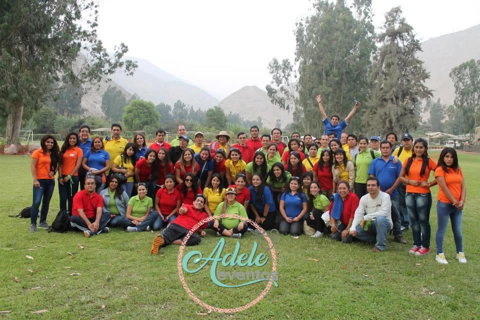 Integrantes de un equipo corporativo vestidos con polo de colores posando en grupo durante una jornada de integración al aire libre en Cieneguilla por Adele Eventos.