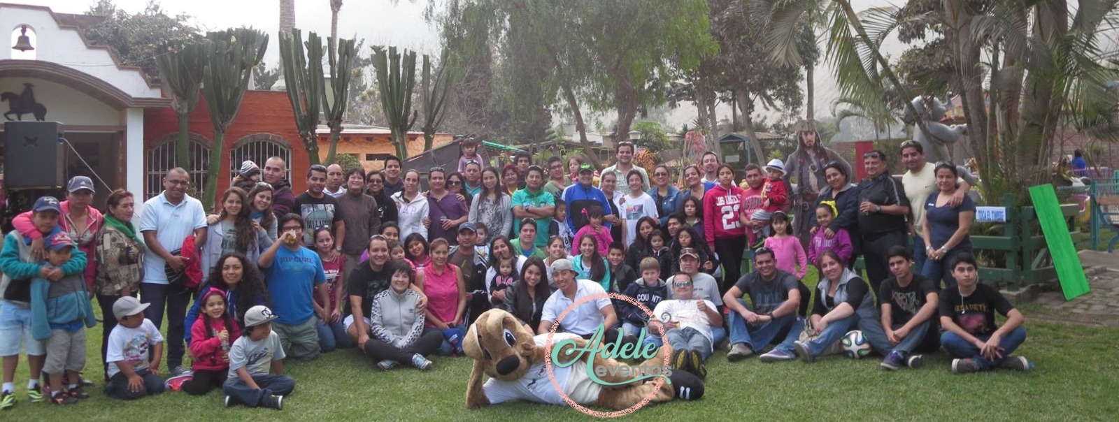 Gran grupo de colaboradores y sus familias posando en un área verde durante un evento corporativo en Cieneguilla por Adele Eventos.